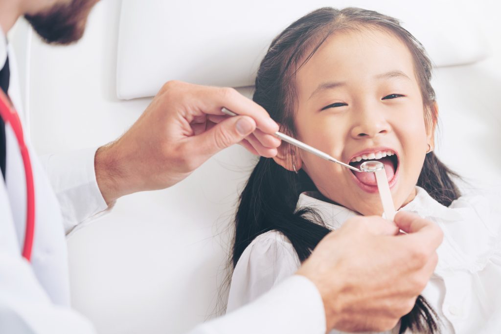 Dentist examining child teeth in dental clinic.